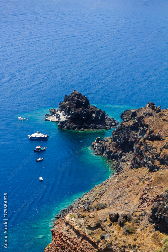 Boats in the sea near the coast of Oia village on Santorini island, Greece