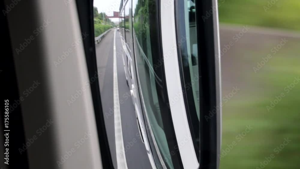 View of the rear-view mirror of a bus running on the road.