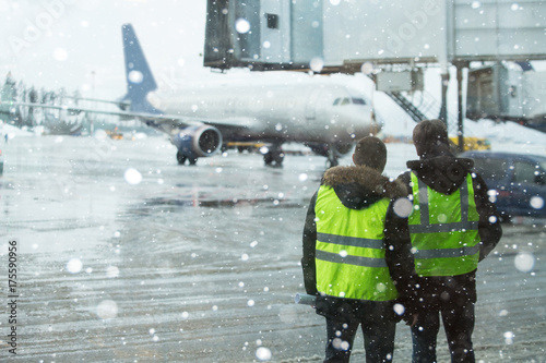 Fotografija Airport managers standing under snowfall.