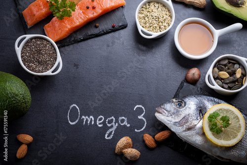 Black slate table with product rich in omega 3 and vitamin D. Written word omega 3 by white chalk.