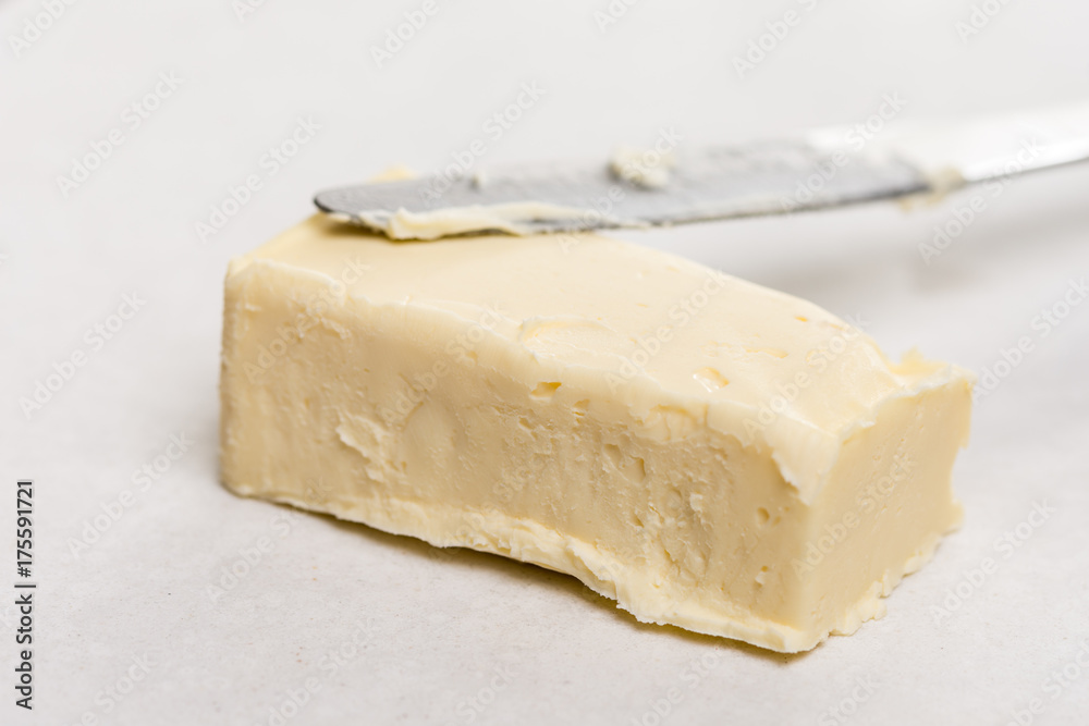 Slice of butter with kitchen knife on the white marble background table