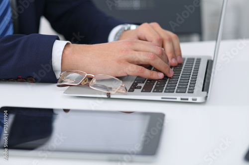 Businessman working by typing on laptop computer. Man's hands on notebook or business person at workplace. Employment or start-up concept