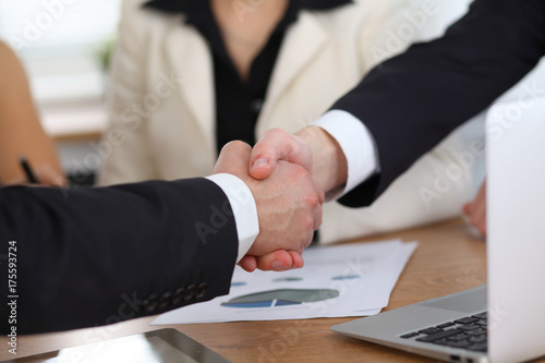 Close up of business people shaking hands at meeting or negotiation in the office. Partners are satisfied because signing contract