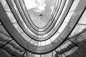 Flying airplane and modern architecture building, low angle black and white abstract looking picture 