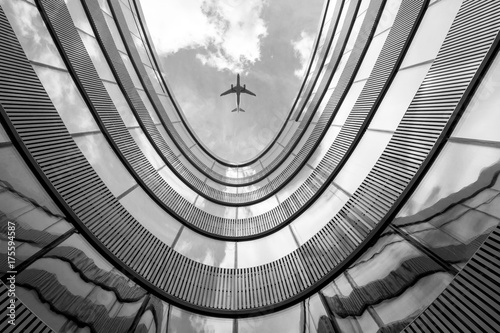 Flying airplane and modern architecture building, low angle black and white abstract looking picture 