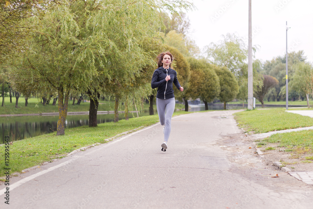 Young happy woman jogging in autumn park. Running Fitness girl