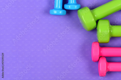 Dumbbells made of pink, green and blue plastic on purple