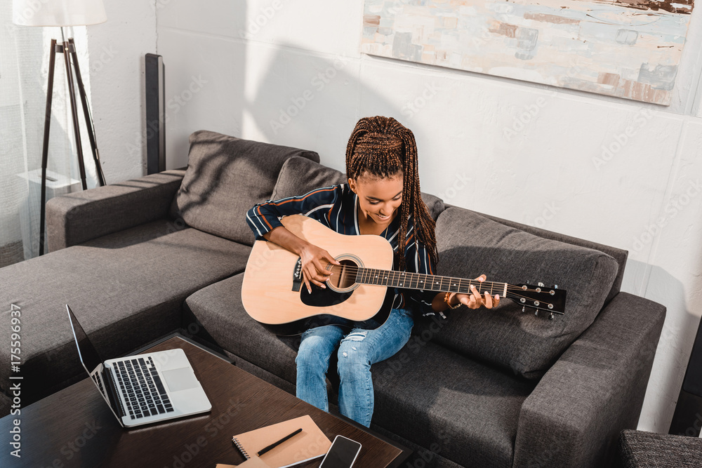 Fototapeta woman playing guitar on couch