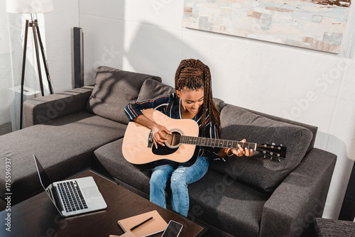 Fototapeta  woman playing guitar on couch