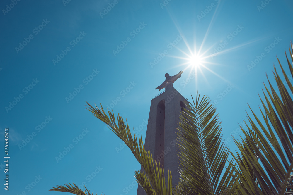 Εκτύπωση καμβά Christ the King Statue through green palm leaf at clear summer sunny day in Lisb