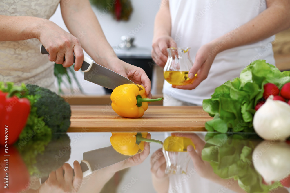 Close-up of human hands cooking in a kitchen. Friends having fun while preparing fresh salad. Vegetarian, healthy meal and friendship concept Close-up of human hands cooking in a kitchen. Friends having fun while preparing fresh salad. Vegetarian, healthy meal and friendship concept
