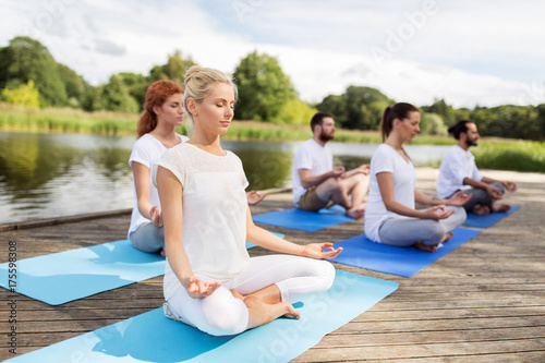 people meditating in yoga lotus pose outdoors