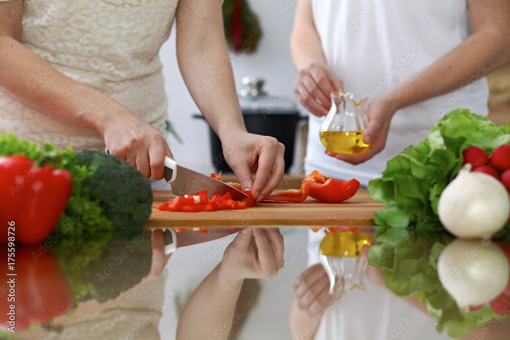 Close-up of human hands cooking in a kitchen. Friends having fun while preparing fresh salad. Vegetarian, healthy meal and friendship concept Close-up of human hands cooking in a kitchen. Friends having fun while preparing fresh salad. Vegetarian, healthy meal and friendship concept