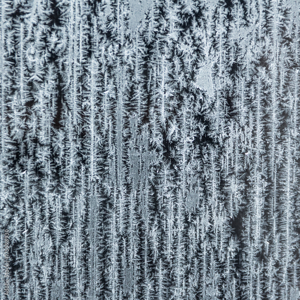 Frozen glass with vertical snow patterns. A square image.