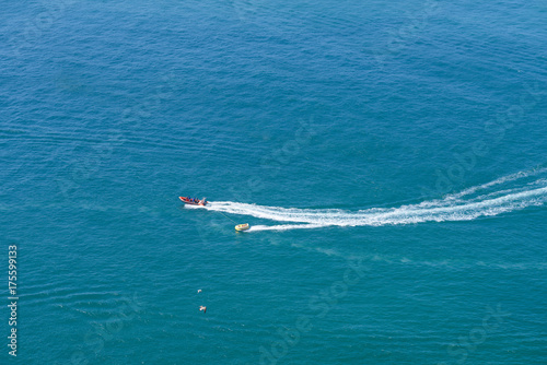 Tourists taking ride by speed boat on rubber tube boat on waves in ocean, birds eye view
