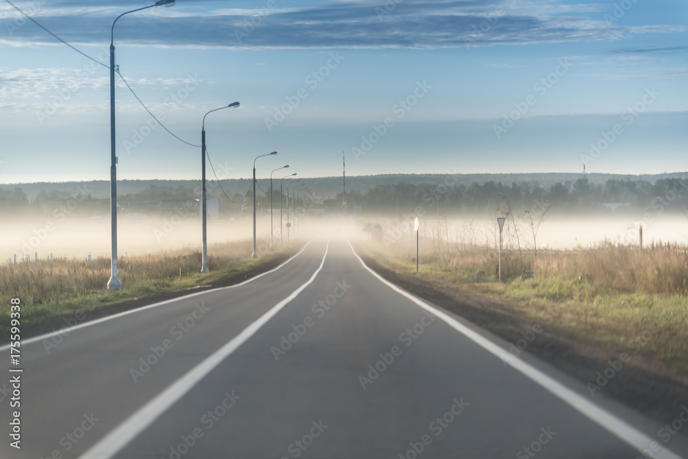 Driving on an empty highway in the mornig with sun and fog