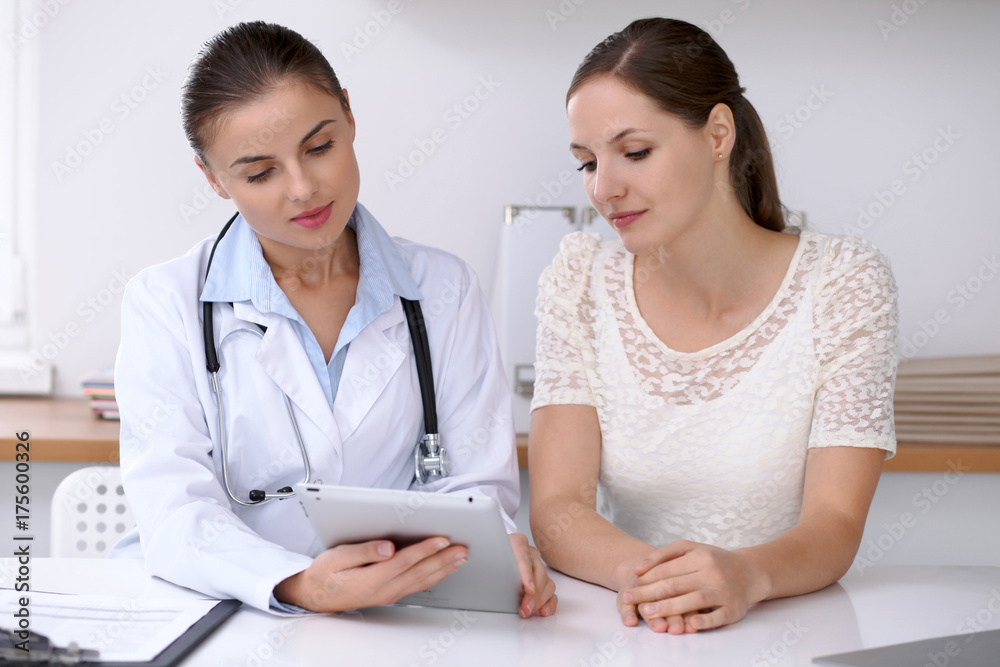 Doctor and patient sitting at the desk. Physician pointing into laptop computer. Medicine and health care concept Doctor and patient sitting at the desk. Physician pointing into laptop computer. Medicine and health care concept