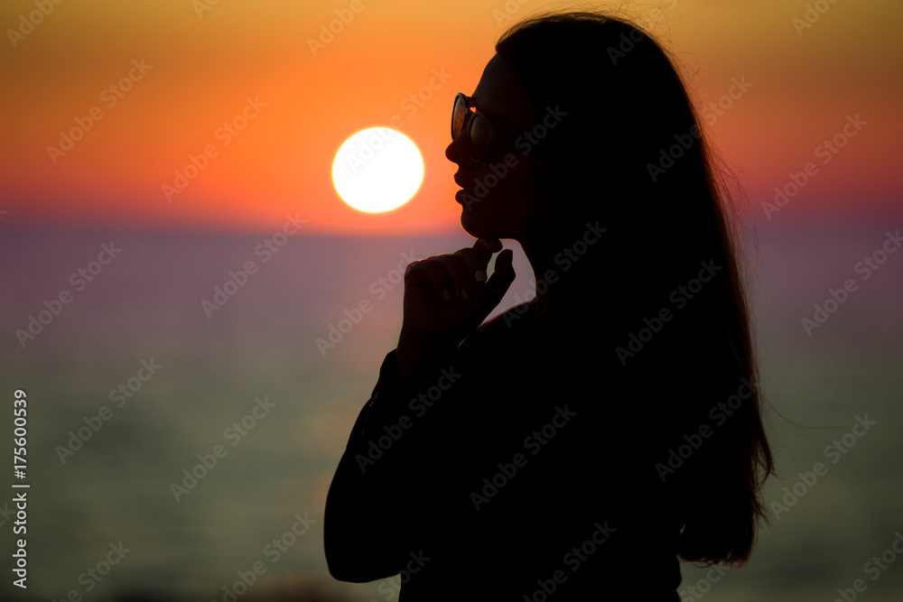 Silhouette of pretty woman over sunset on the beach