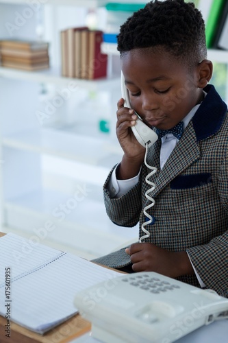 Businessman talking on landline phone while looking at book photo