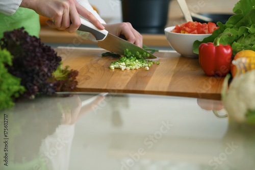 Closeup of human hands cooking vegetables salad in kitchen on the glass table with reflection