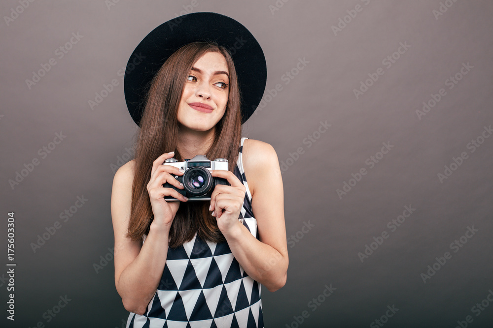 Stylish woman photographer with retro camera on the grey wall background. Image with copy space
