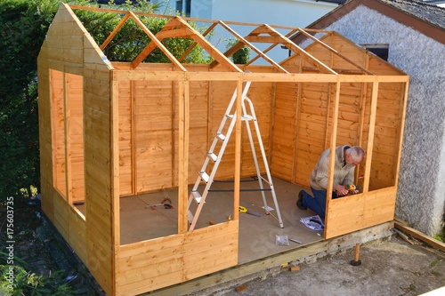 Man at work, completing building of a cabin, shed, summer house.