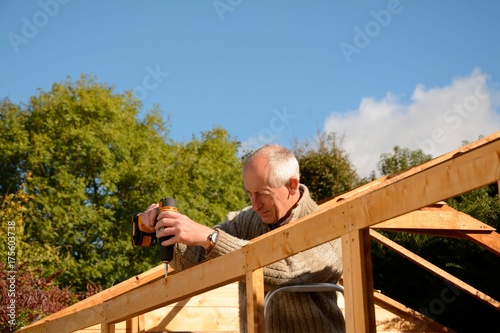 Man at work drilling woodwork outside on sunny day