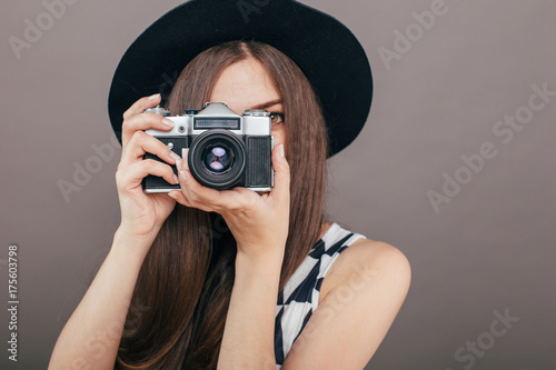 Stylish woman photographer with retro camera on the grey wall background. Image with copy space
