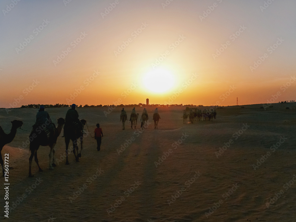 Tourists and bedouins on camels meet sunset in Sahara desert. Tunisia. Tourists and bedouins on camels meet sunset in Sahara desert. Tunisia.