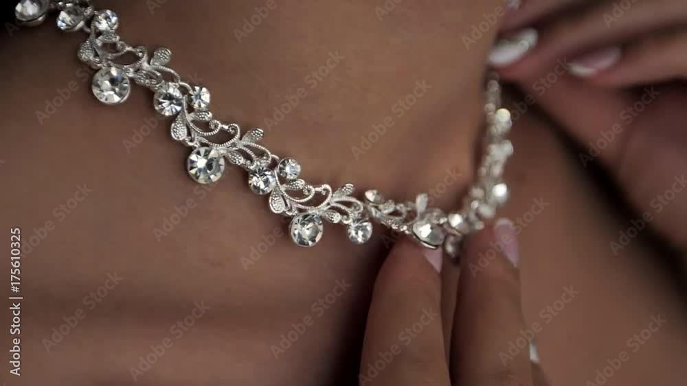Young woman puts on a beautiful necklace Young woman puts on a beautiful necklace