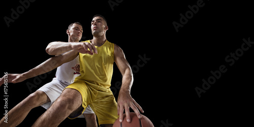 Two basketball players fight for the basketball ball. Isolated basketball players on a black background. Player wears unbranded clothes. Bottom view.