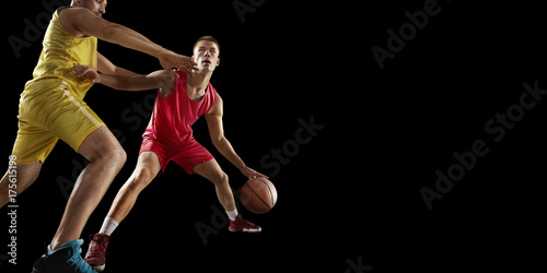Two basketball players fight for the basketball ball. Isolated basketball players on a black background. Player wears unbranded clothes.