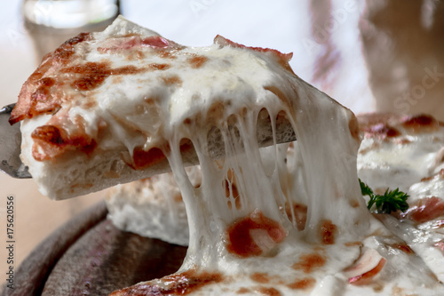 Close up Italian pizza about cheese it stick. Selective focus.Slice of hot pizza large cheese lunch or dinner crust seafood meat topping sauce.Hot Homemade Pepperoni Pizza Ready to Eat