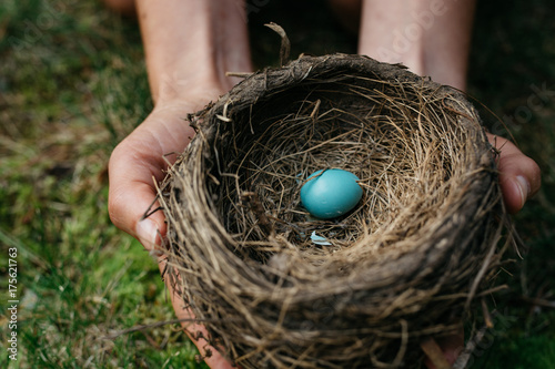 Woman holding a robin's nest with one egg in it