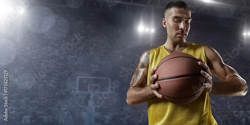 Basketball player hold a basketball ball on big professional arena. Player wears unbranded clothes. © Alex
