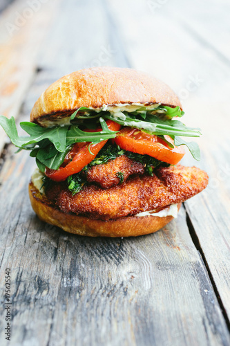 Fried chicken sandwich on bread sitting on wooden surface - digital file