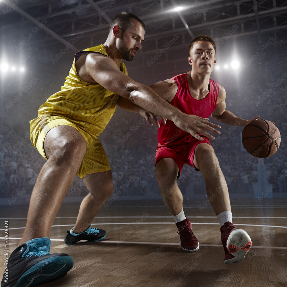 Fototapeta premium Two basketball players fight for the basketball ball on big professional arena. Player wears unbranded clothes.