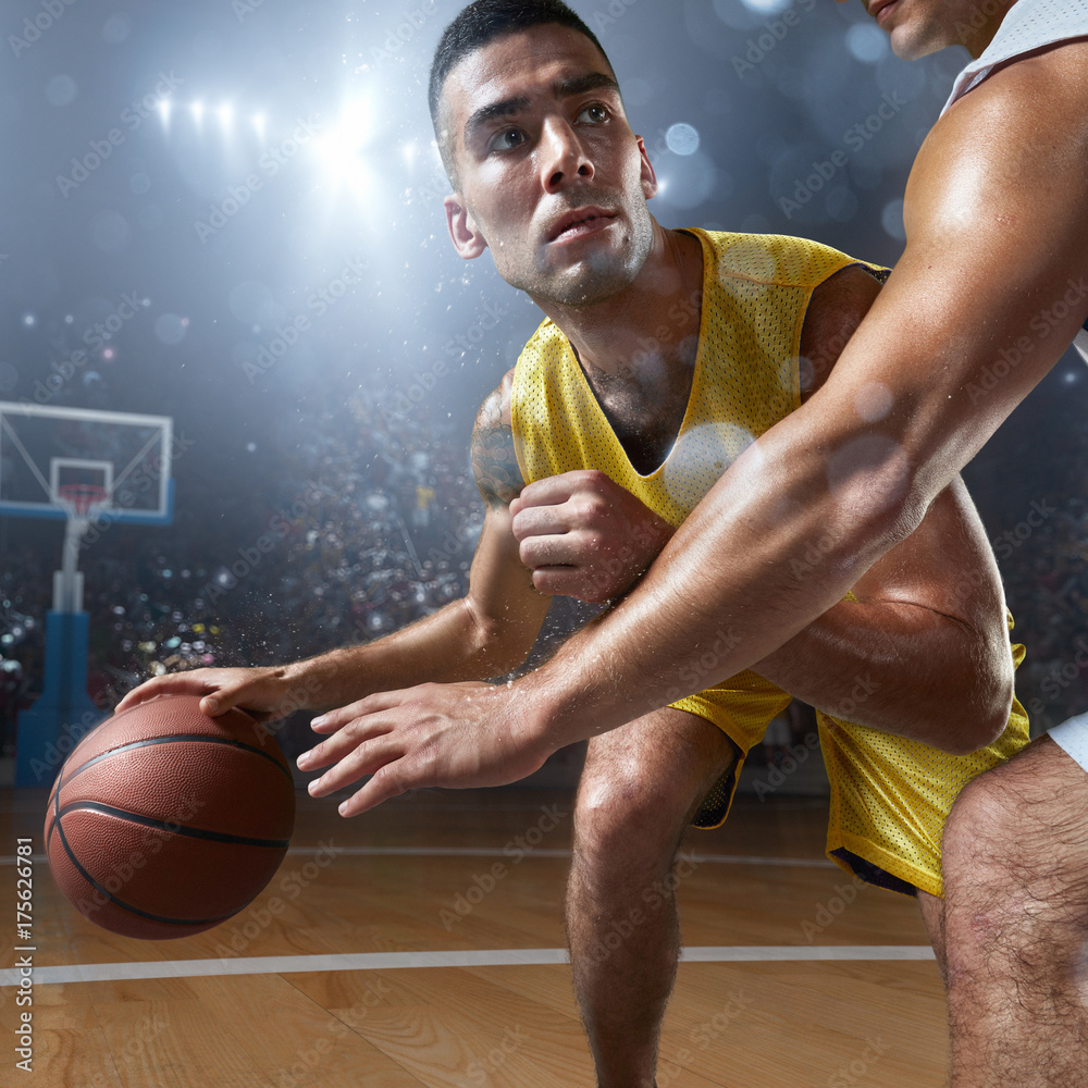 Two basketball players fight for the basketball ball on big professional arena. Player wears unbranded clothes. Two basketball players fight for the basketball ball on big professional arena. Player wears unbranded clothes.