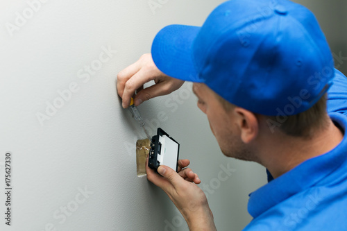 electrician installing light switch on the wall photo