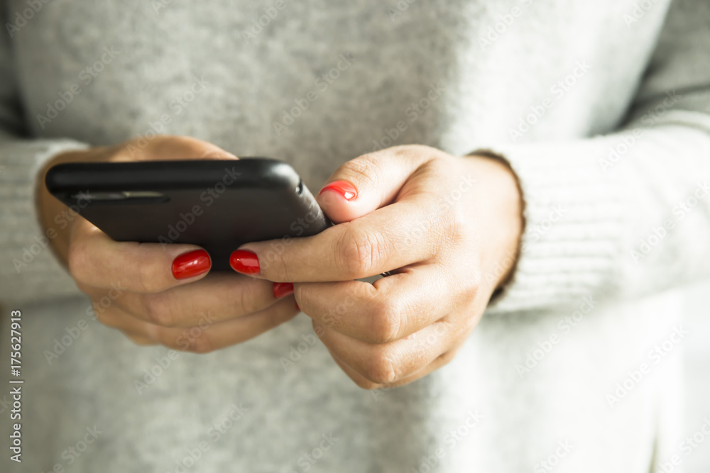 girl with red nails holding a smartphone in a black case girl with red nails holding a smartphone in a black case
