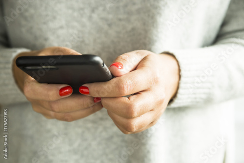 Εκτύπωση καμβά girl with red nails holding a smartphone in a black case