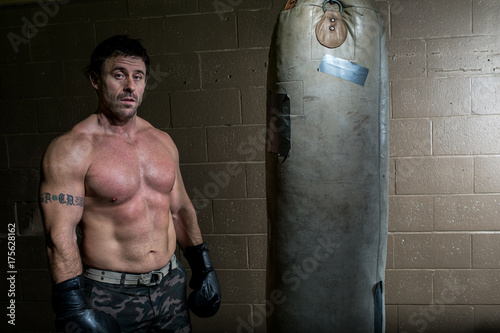 A boxer stands next to a punching bag