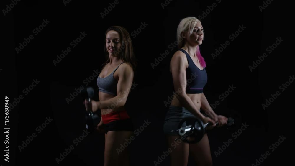 2 Fit young women working out with weights against a black background 2 Fit young women working out with weights against a black background