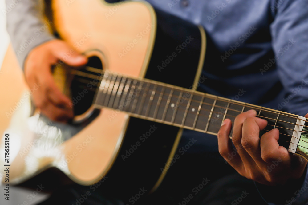 Fototapeta premium Practicing in playing guitar. Handsome young men playing guitar