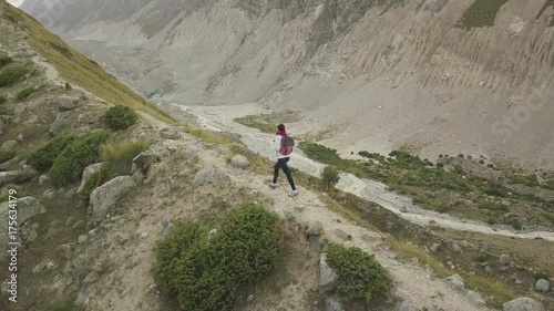 Girl walking along narrow summit ridge crest in the evening