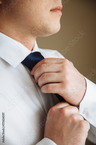 Businessman in white shirt tying the necktie