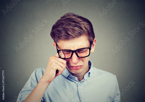 Closeup portrait of a crying teenager man in glasses