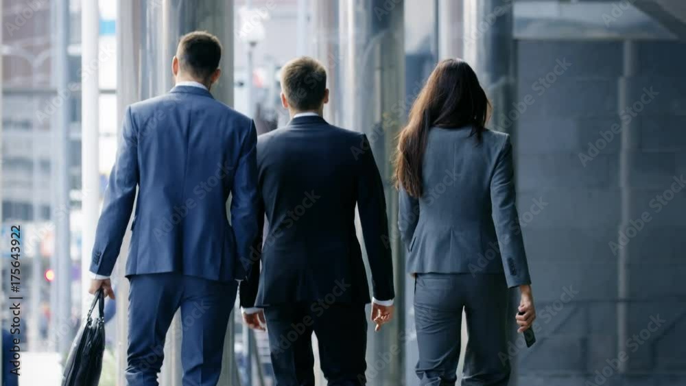 Back View of Three Business People Walking in the Central Business District. Shot on RED EPIC-W 8K Helium Cinema Camera. Back View of Three Business People Walking in the Central Business District. Shot on RED EPIC-W 8K Helium Cinema Camera.