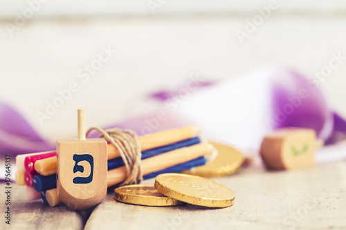 Hanukkah dreidels with some Hanukkah candles and Hanukkah coins on a vintage wood background with copy space.