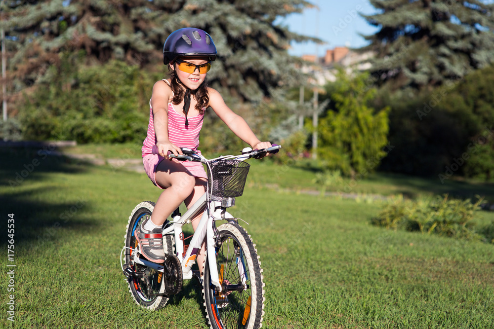 Portrait of a little girl in helmet on a bicycle in summer park Portrait of a little girl in helmet on a bicycle in summer park